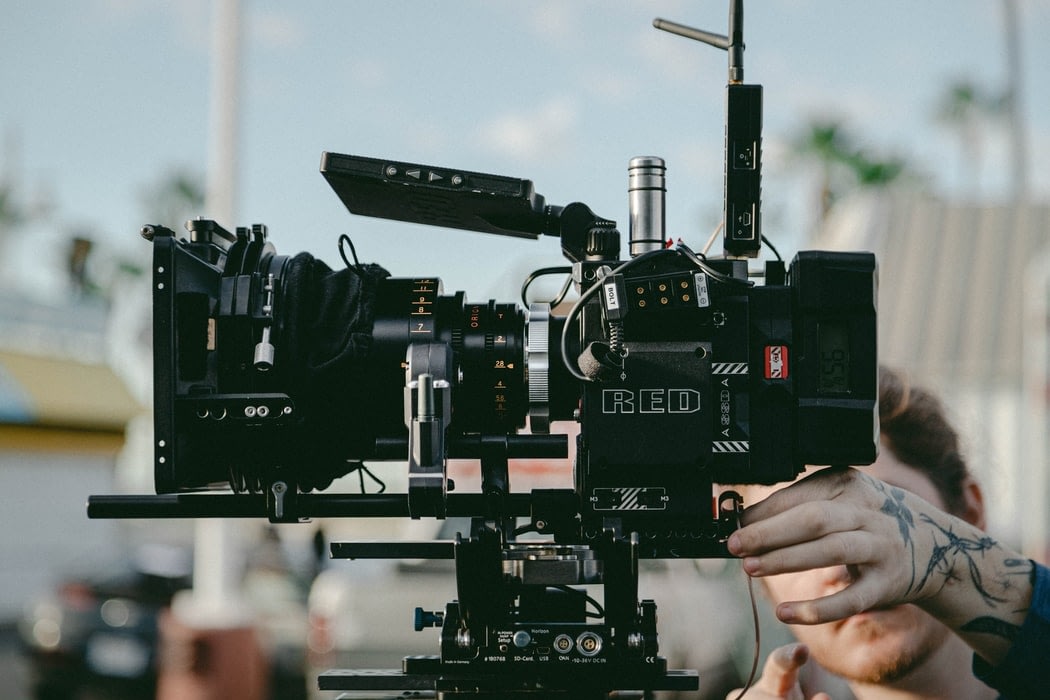 Close up image of a Red camera and a man operating it.