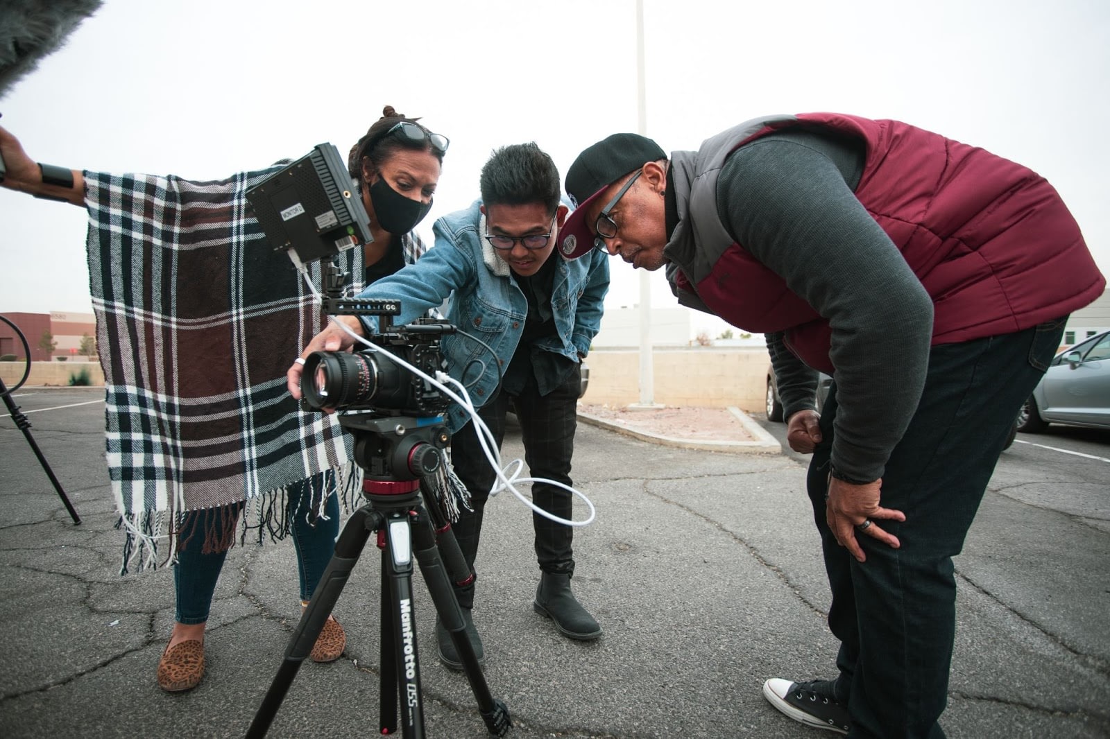 group of people bending over and looking into a camera monitor on a movie set.