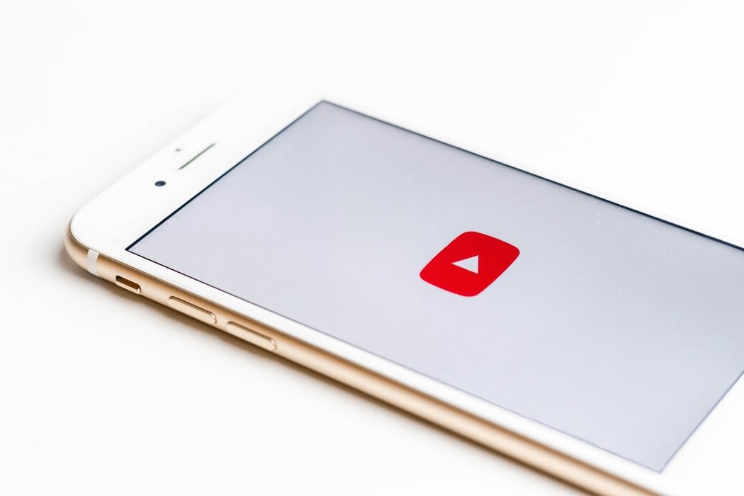 White cellphone laying horizontally with the Youtube logo displayed.